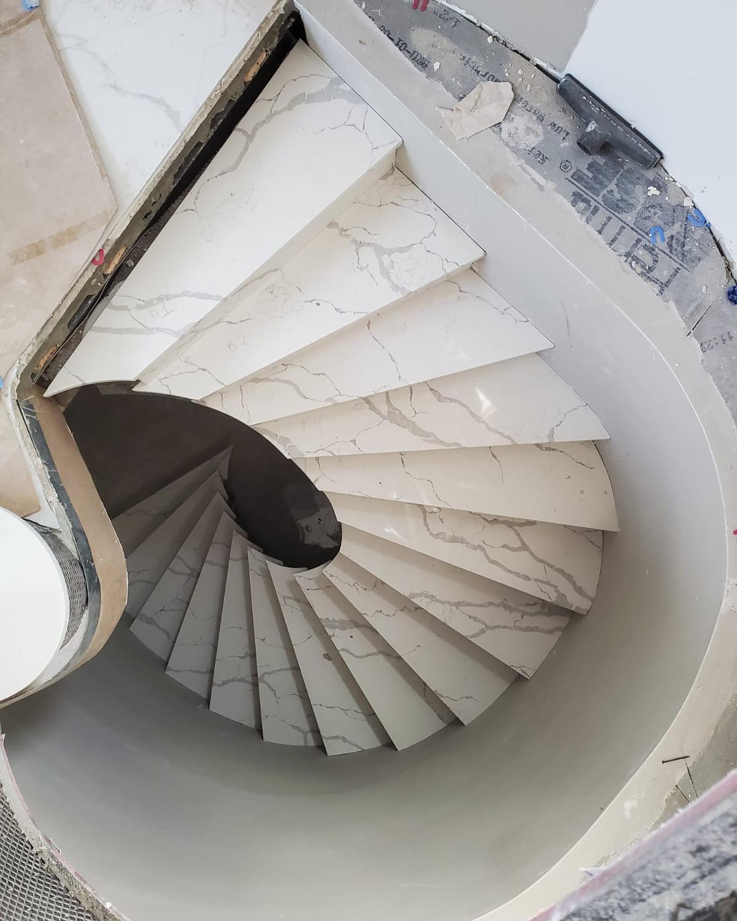 Spiral quartz Calacatta staircase by Fine Stone Works